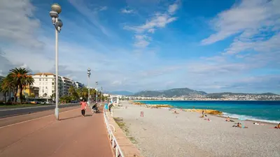 a group of people walking on a beach at Studio Calif, face tram proche Mer in Nice