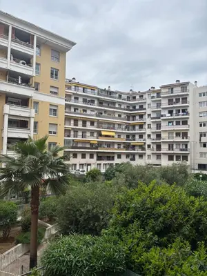 a large apartment building with a palm tree in the foreground at Studio Calif, face tram proche Mer in Nice