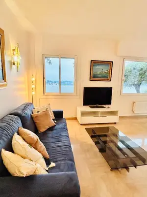 a living room with a black couch and a tv at Golden Mornings, Sea, Garden, Breakfast & Free Parking in Villefranche-sur-Mer
