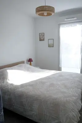 a white bedroom with a large bed and a window at Sea view apartment close to beaches in Cagnes-sur-Mer
