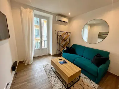 a living room with a green couch and a mirror at Studio calme et central avec clim in Nice