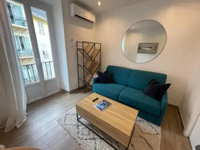 a living room with a blue couch and a mirror at Studio calme et central avec clim in Nice