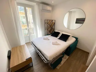 a bedroom with a bed with a mirror on the wall at Studio calme et central avec clim in Nice