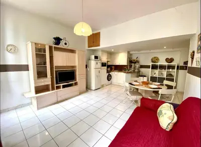 a living room with a red couch and a kitchen at 2 pièces avec clim proche place Masséna in Nice
