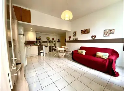 a living room with a red couch and a kitchen at 2 pièces avec clim proche place Masséna in Nice