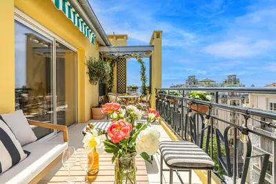 a balcony with a couch and a table with flowers at Luxurious penthouse, 2 bedroom suites, 3 spacious terraces, gorgeous views of mountains and sea, in Nice