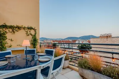 a balcony with a table and chairs and a view at Luxurious penthouse, 2 bedroom suites, 3 spacious terraces, gorgeous views of mountains and sea, in Nice