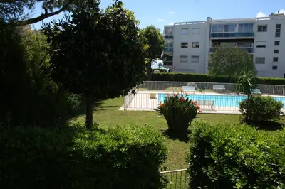 a swimming pool in a park with a building at Rez de jardin en bord de mer in Cagnes-sur-Mer
