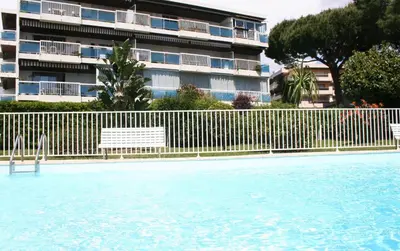 a swimming pool with a fence and a building at Rez de jardin en bord de mer in Cagnes-sur-Mer