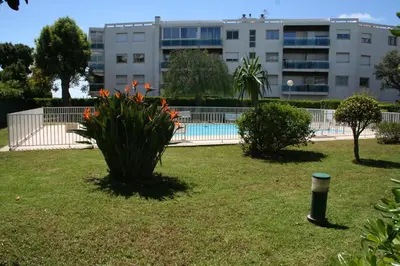 a building with a swimming pool in a yard at Rez de jardin en bord de mer in Cagnes-sur-Mer