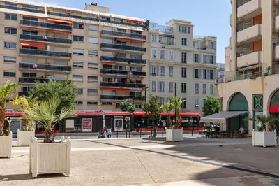 a city street with buildings and palm trees and a bus at HAPPYFEW Le Palais des Arts in Nice