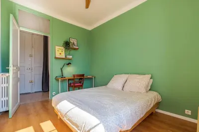 a green bedroom with a bed and a table at 3 pieces lumineux avec balcon au coeur de la ville in Nice