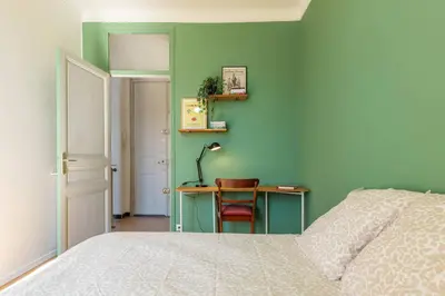 a bedroom with a bed and a desk with a lamp at 3 pieces lumineux avec balcon au coeur de la ville in Nice