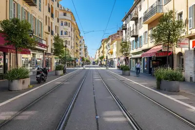 an empty street with train tracks in a city at 3 pieces lumineux avec balcon au coeur de la ville in Nice