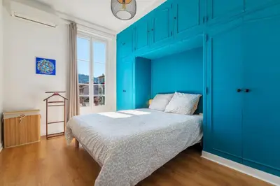 a blue bedroom with a bed with a blue headboard at 3 pieces lumineux avec balcon au coeur de la ville in Nice
