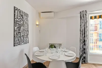 a white dining room with a white table and chairs at Suite de Dijon FSHH in Nice