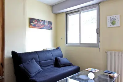a living room with a blue couch and a window at Studio climatisé au calme, terrasse vue colline in Nice