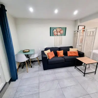 a living room with a black couch and a table at Spacious studio full of charm, recently updated in Nice