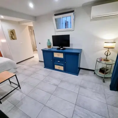 a room with a blue cabinet with a television on it at Spacious studio full of charm, recently updated in Nice