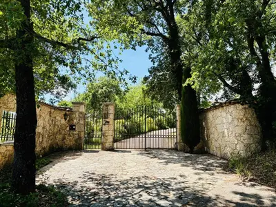 a gate with trees in front of a stone fence at Hacienda Provençale- Piscine, Pétanque et Plenitude in Saint-Jeannet
