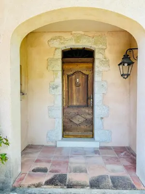 a large wooden door in a stone wall with a lamp at Hacienda Provençale- Piscine, Pétanque et Plenitude in Saint-Jeannet
