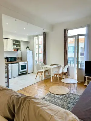 a living room with a table and chairs and a kitchen at 3p proche Port in Nice