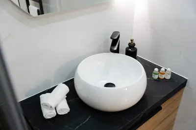 a bathroom with a white sink on a black counter at Ambiance cosy a la Niçoise in Nice