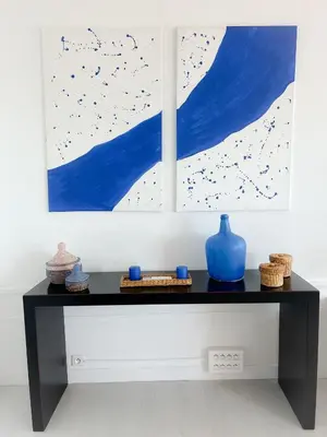 a black table with a blue vase and two paintings at Les pieds dans l eau in Nice