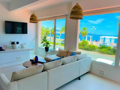 a living room with a white couch and a large window at Les pieds dans l eau in Nice