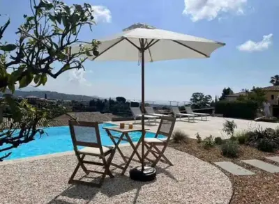a table and two chairs under an umbrella next to a pool at DOMAINE LOU BEL AZUR - Paisible in Saint-Laurent-du-Var