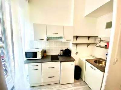 a small kitchen with white cabinets and a microwave at Joli studio cœur de Nice in Nice