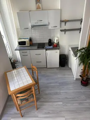 a kitchen with white cabinets and a table and a chair at Joli studio cœur de Nice in Nice