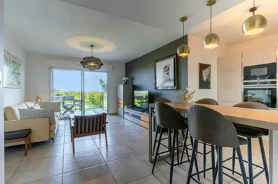 a kitchen and living room with a table and chairs at Azur Panoramique – Calme Vue Mer proche Nice in Saint-Laurent-du-Var