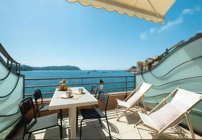 a balcony with a table and chairs and the water at Vue Mer Prestige in Villefranche-sur-Mer