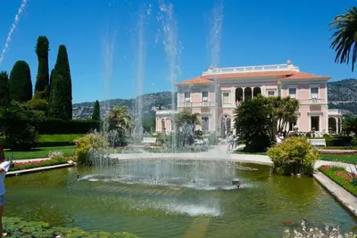 a large building with a fountain in front of a pond at Vue Mer Prestige in Villefranche-sur-Mer
