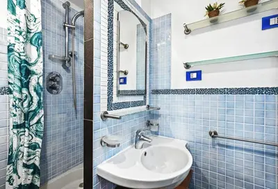 a blue tiled bathroom with a sink and a mirror at Vue Mer Prestige in Villefranche-sur-Mer