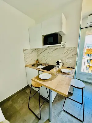 a small kitchen with a wooden table and two chairs at Sweethome Massena in Nice