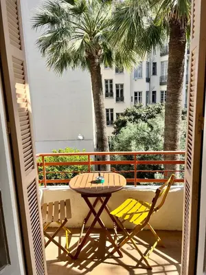 a table and chairs on a balcony with palm trees at Charmant appartement avec terrasse en plein cœur de Nice à deux pas de la mer ! in Nice