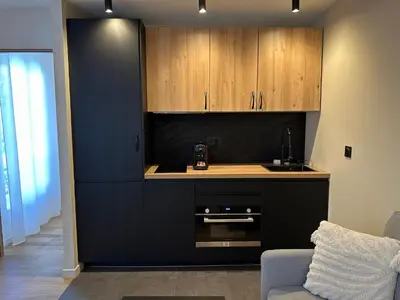 a kitchen with a black counter and wooden cabinets at Côté Mer - Élégant 3 pièces, Wifi et climatisation in Nice