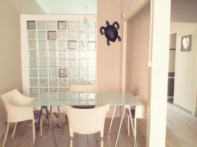 a dining room with a glass table and white chairs at Joli 2 pièces à 2 min de la plage in Nice