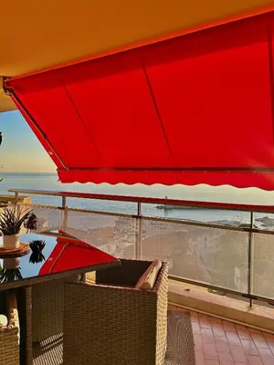 a red umbrella on a balcony with a table and chairs at Magnifique appartement - Vue mer in Nice