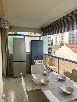 a kitchen with a table with chairs and a refrigerator at Appartement cosy à 200 m de la mer in Cagnes-sur-Mer