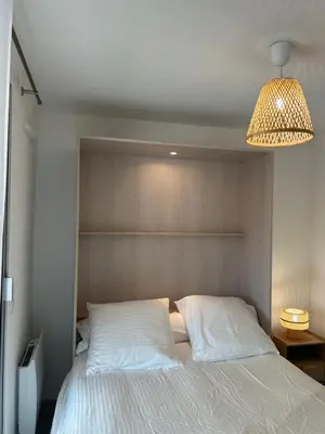 a bedroom with a white bed with a light fixture at Appartement cosy à 200 m de la mer in Cagnes-sur-Mer