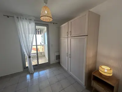 a living room with a cabinet and a window at Appartement cosy à 200 m de la mer in Cagnes-sur-Mer