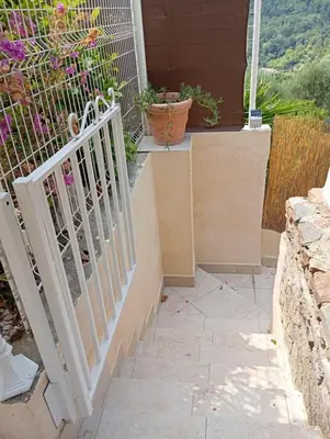 a set of stairs leading up to a house with flowers at maison individuelle in Tourrette-Levens