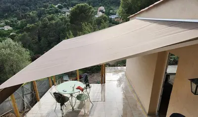 a white awning on a balcony with a table and chairs at maison individuelle in Tourrette-Levens