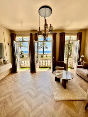 a living room with a table and a view of the ocean at Le Petit Palace in Nice
