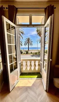 an open door to a balcony with a view of the ocean at Le Petit Palace in Nice
