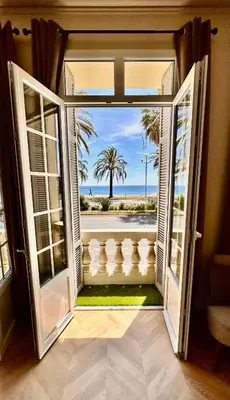 an open door to a balcony with a view of the ocean at Le Petit Palace in Nice