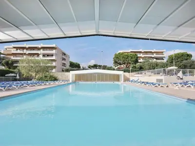 a large swimming pool with chairs and a building at Studio 50M de la mer in Saint-Laurent-du-Var